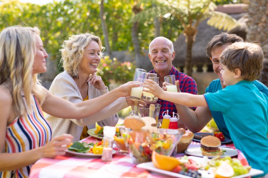 Happy caucasian three generational family toasting drinks at table in the garden. family, togetherness and weekend lifestyle concept, unaltered.